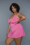 Plus-size woman in pink lingerie dress with lace trim, posing confidently against gray background