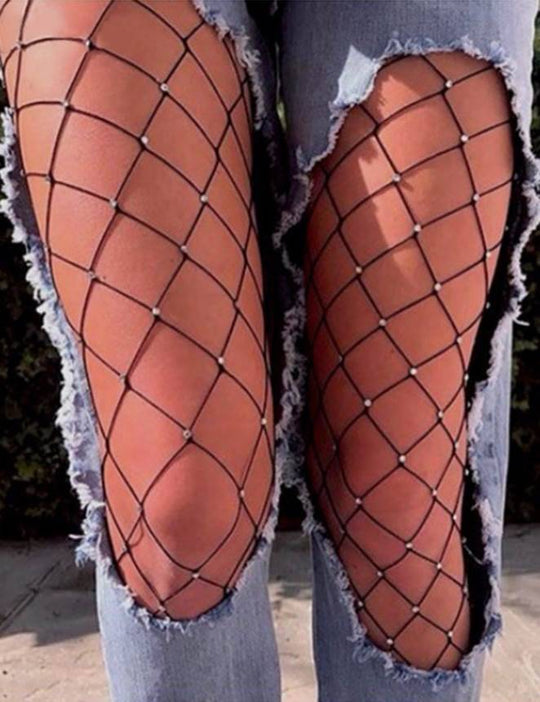 Person wearing black fishnet stockings with a ripped denim outfit.