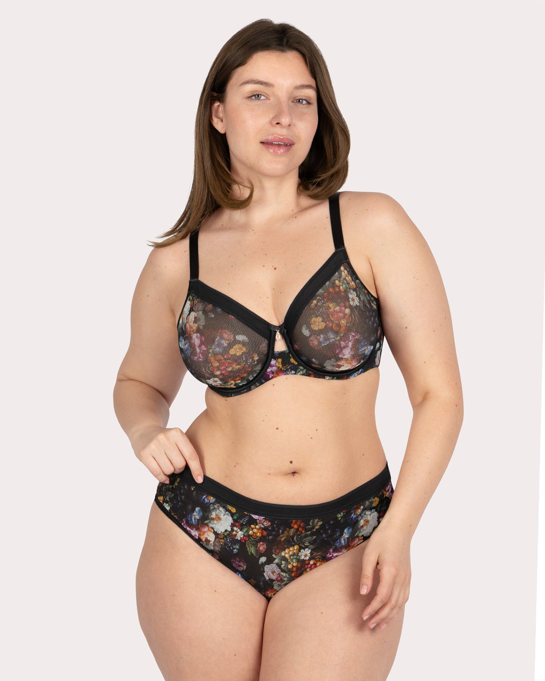 Woman wearing a floral lingerie set on a plain background