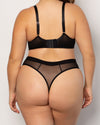 A model shown from the back wearing a black mesh and satin lingerie set, consisting of a bralette with adjustable straps and matching high-waisted thong with sheer mesh panels.