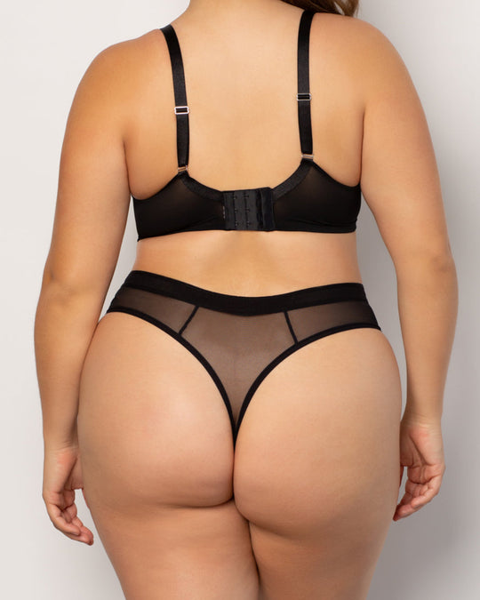 A model shown from the back wearing a black mesh and satin lingerie set, consisting of a bralette with adjustable straps and matching high-waisted thong with sheer mesh panels.