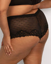 Black sheer mesh panties with a polka dot pattern and lace trim, shown on a model from the back against a light gray background.