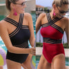 Two swimsuits, one black and one red, worn by a model by a pool.