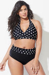 Woman wearing a black polka dot bikini against a white background