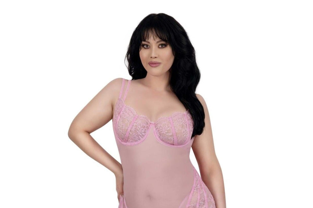 A woman modeling a light pink sheer lace babydoll lingerie bodysuit with underwire cups, photographed against a solid white background.